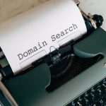 Schreibmaschine mit eingelegtem Blatt, darauf der Text "Domain Search"